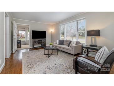 Cozy living room featuring neutral tones, hardwood floors, a large window, and comfortable seating at 3231 Eastwood Dr, Charlotte, NC 28205