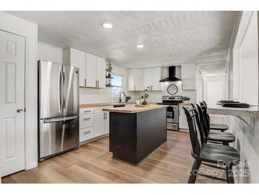 Bright kitchen boasts white cabinets, stainless steel appliances, butcher block counters, and a central island at 3598 Puett Park Dr, Conover, NC 28613