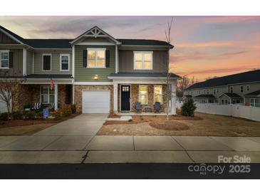 Charming two-story townhouse showcasing stone accents, a one-car garage and a welcoming front porch at 8157 Merryvale Ln, Charlotte, NC 28214