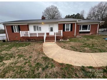 Charming brick home featuring a metal roof, white trim, and inviting walkway leading to the front door at 920 Oakridge Farm Hwy, Mooresville, NC 28115