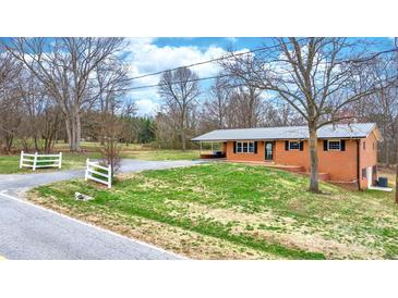 Charming brick home with metal roof, green lawn, driveway and white picket fence at 104 Pop Davis Rd, Taylorsville, NC 28681
