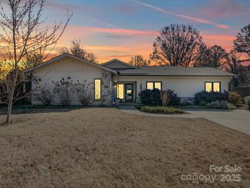 Charming single-story home featuring stone accents and a well-maintained front yard under a colorful sunset sky at 1207 Lakedell Dr, Charlotte, NC 28215