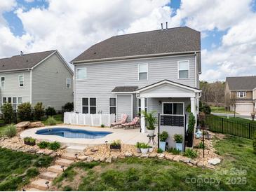 Beautiful backyard with a small inground pool, patio, landscaping, and gray two story home at 2033 Folkstone Ln, Lancaster, SC 29720