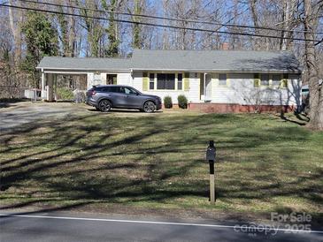 Charming single-story home with mature trees and a car parked in the carport at 5924 Freedom Dr, Charlotte, NC 28214