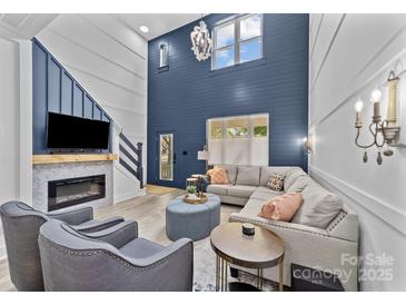 Bright living room boasts a cozy fireplace and soaring ceilings with elegant chandelier at 8123 Village Harbor Dr, Cornelius, NC 28031