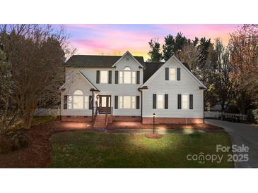 Charming two-story home with white siding, black shutters, and a well-manicured lawn at dusk at 1509 Orange Hill Ct, Gastonia, NC 28056