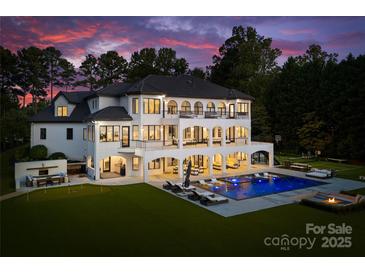 Expansive backyard featuring a pool with water features, lounge areas, a fire pit, and a covered outdoor living space at 16439 Jetton Rd, Cornelius, NC 28031