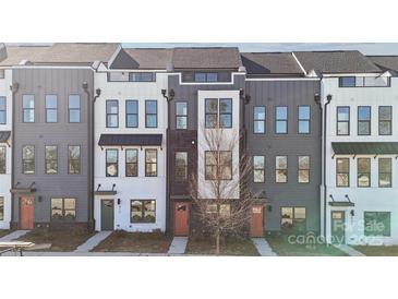 Modern townhome exterior showcasing a gray and white facade, with a view of the front doors and surrounding landscape at 421 Blairhill Rd # 11, Charlotte, NC 28217