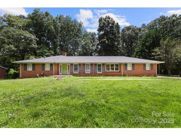 Ranch-style brick home with large front yard and mature trees offers classic charm and curb appeal at 1210 Brookwood Dr, Shelby, NC 28150