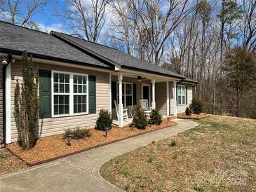 Charming single-story home featuring a welcoming front porch and landscaped yard with mature trees at 321 Creek Se Trl, Concord, NC 28025
