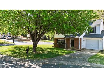 Charming two-story home with lush green lawn and mature tree providing shade at 303 Cupped Oak Ct, Charlotte, NC 28213