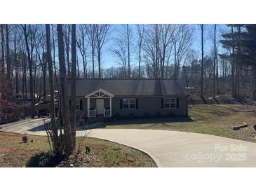 Charming single-story home with a long driveway and a welcoming front porch nestled amongst trees at 312 Sailwinds Rd, Mooresville, NC 28115