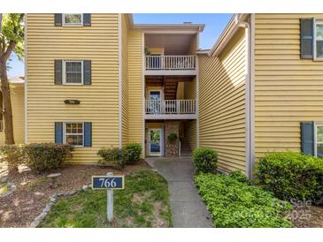 Charming condo exterior with yellow siding, blue shutters, and a welcoming entrance with multiple balconies at 766 Marsh Rd # Apt 2, Charlotte, NC 28209