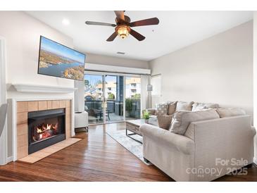 Inviting living room featuring a cozy fireplace, ceiling fan, and sliding glass doors to the balcony at 1107 Torrence Cir, Davidson, NC 28036