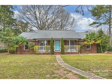 Charming brick home with a welcoming front porch and lush landscaping, enhanced by a pathway to the front door at 117 Maple Hill Rd, Monroe, NC 28110