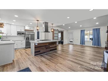 Open living room and kitchen with stainless appliances and wood flooring at 1536 Plyler Lake Rd, Gastonia, NC 28054