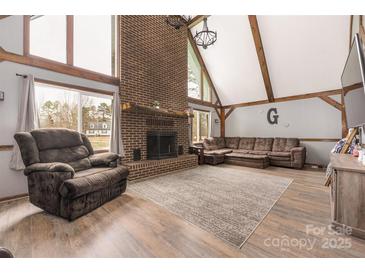 Inviting living room with a brick fireplace, wood-look floors, a comfortable sectional sofa, and large windows at 360 Patience Dr, Concord, NC 28025