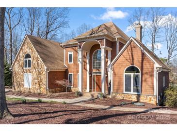 Charming two-story home showcasing a blend of stone and cedar shake siding with a covered front entry at 20338 Christofle Dr, Cornelius, NC 28031