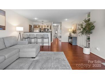 Open living room features bar seating to the kitchen with hardwood floors and neutral tones at 529 N Graham St # 2G, Charlotte, NC 28202