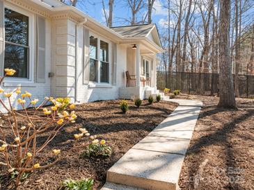 Charming white brick home with manicured lawn and inviting walkway, with beautiful landscaping at 6215 Coatbridge Ln, Charlotte, NC 28212