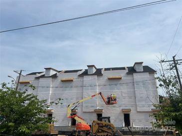 A building under construction with construction workers and equipment, under a blue sky at 3018 Casting St # 20, Charlotte, NC 28206
