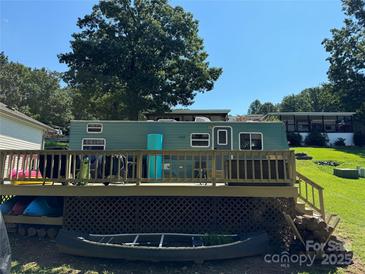 Charming mobile home with a wooden porch, perfect for outdoor relaxation and enjoyment at 104 Trestle Cir, New London, NC 28127