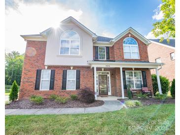 Charming two-story brick home with a manicured lawn, rocking chairs on the front porch, and black shutters at 10836 Clark St, Davidson, NC 28036