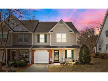 Inviting townhouse featuring a one-car garage, charming front porch, and lush landscaping at 2592 Brackley Nw Pl, Concord, NC 28027