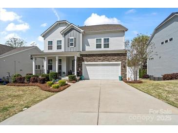 Charming two-story home with a stone accent, landscaped yard, covered porch, and an attached two-car garage at 7200 Irongate Dr, Indian Land, SC 29707