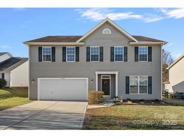 Charming two-story home with a well-maintained lawn, attached garage, and inviting front entrance at 1009 Rocky Meadows Ln, Concord, NC 28025