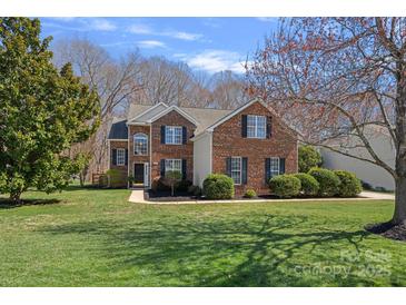 Charming two-story brick home featuring a manicured lawn, lush landscaping, and classic architectural details at 1161 Woodwinds Dr, Waxhaw, NC 28173