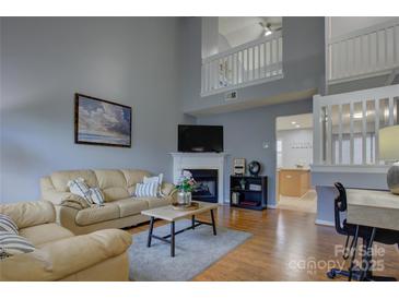 Bright living room featuring a fireplace, hardwood floors, and a staircase to the second floor at 12928 Sickles Dr, Charlotte, NC 28273