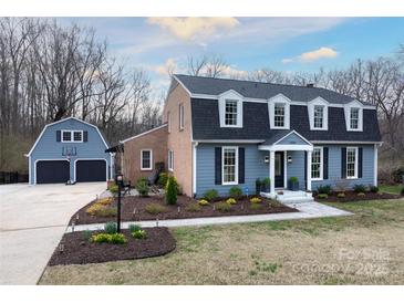 Charming two-story home with blue siding, black shutters, and a detached two-car garage at 4000 Bridgewood Ln, Charlotte, NC 28226