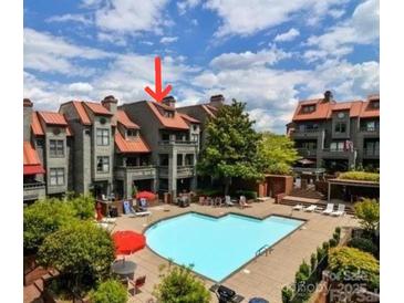 Exterior view of community pool and lounging area surrounded by gray townhomes with reddish-brown roofs at 9037 J M Keynes Dr, Charlotte, NC 28262