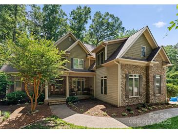 Charming exterior showcasing a stone and siding facade, complemented by a well-manicured lawn and mature trees at 109 Hawksnest Ln, Mooresville, NC 28117