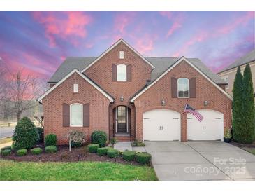 Charming two-story brick home with a two-car garage, manicured lawn, and an American flag at 16620 Redding Park Ln, Cornelius, NC 28031