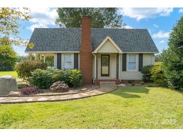 Charming cottage-style home featuring a brick chimney, lush landscaping, and a welcoming front entrance at 7740 Us 52 Hwy, Salisbury, NC 28146