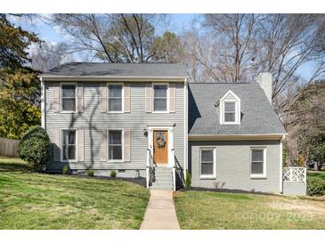 Charming two-story home with a beautiful gray exterior, landscaped yard and cozy wooden front door at 5019 Crooked Oak Ln, Charlotte, NC 28226