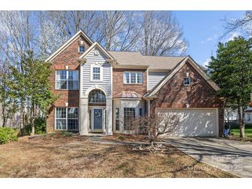 Charming two-story brick home with attached garage, arched entryway, and manicured front yard at 717 Meadow Lake Dr, Matthews, NC 28105