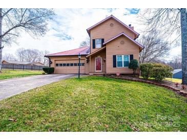 Charming two-story home featuring a red metal roof, a spacious front yard, and an attached two-car garage at 1228 Hidden Creek Cir, Hickory, NC 28602