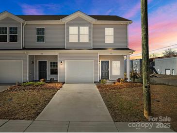 Charming townhome featuring a one car garage, neutral siding, and well manicured landscaping at 136 S Bell Ave, Albemarle, NC 28001
