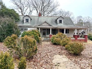 Quaint home with dormers, covered porch, and mature landscaping, awaiting a creative renovation at 2412 Daves Dr, Shelby, NC 28152