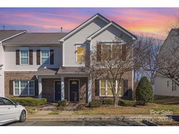 Charming townhome featuring brick accents, neutral siding, a well-maintained lawn and a colorful sunset backdrop at 10530 Stoneacre Ct, Pineville, NC 28134