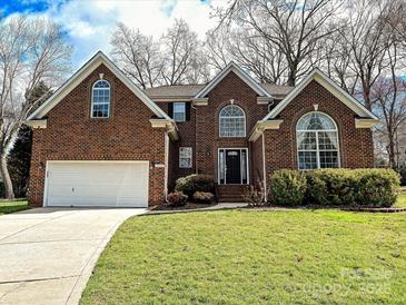 Charming brick home featuring an attached two car garage and a well-manicured lawn at 15715 Holyhead Ln, Huntersville, NC 28078