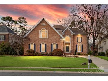 Charming brick home features manicured lawn and dark shutters at dusk at 2300 Bonnie Butler Way, Charlotte, NC 28270