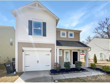 Charming two-story home features a one-car garage and inviting front porch with manicured landscaping at 2609 Riley Woods Ln, Charlotte, NC 28269
