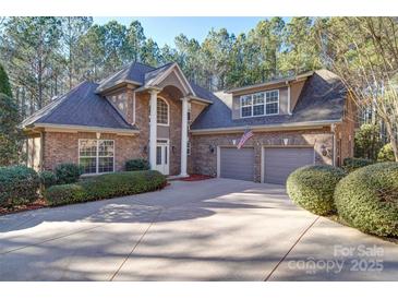 Elegant brick home with a large driveway and three-car garage nestled among mature trees at 4763 River Hills Dr, Denver, NC 28037