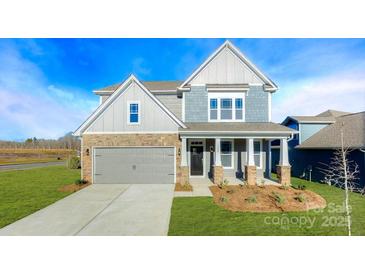 Charming two-story home with a manicured lawn, stone accents, and a welcoming front porch at 7021 Sylvan Retreat Dr, Denver, NC 28037