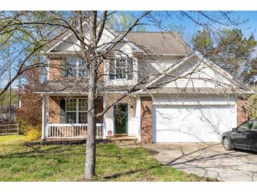 Charming two-story home with a brick and siding exterior, covered porch, and attached garage at 10820 Hunters Trace Ct, Charlotte, NC 28262