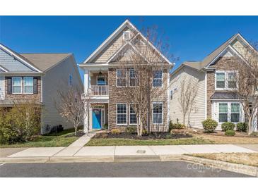 Charming two-story home featuring a stone facade, a blue front door, and a small balcony at 13925 Helen Benson Blvd, Davidson, NC 28036